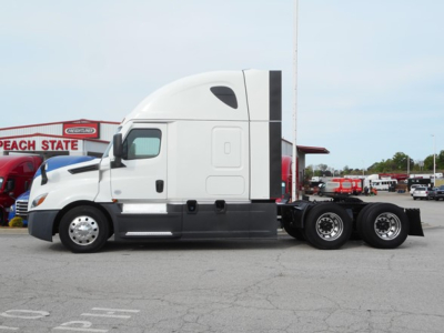 Truck side view: 2023 Freightliner Cascadia 126, Sleeper tractor with white cab, black lower panels, tandem rear axles. Visible text on image includes dealership signage in background reading Peach State.