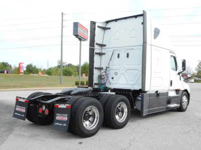 Freightliner Cascadia 126 tractor rear view showing chassis and triple rear axles with fuel tanks and wiring near sleeper cab.