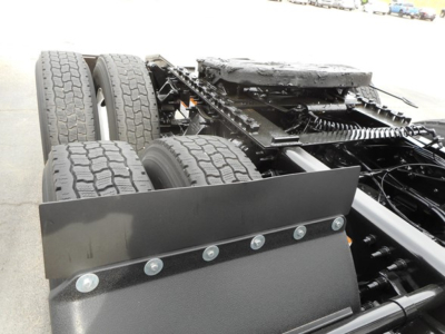 Frontal view of a Freightliner truck chassis showing rear dual axle wheels, undercarriage, and a flat-front snow plow blade attached to the frame.