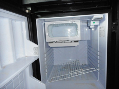 Freightliner Cascadia 126 engine bay showing empty refrigerator compartment? No, it's a small freezer or storage unit inside the sleeper with open door.