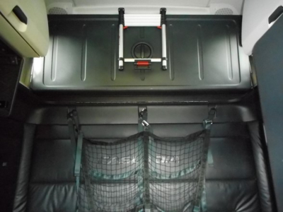 Truck cab interior storage area showing overhead bunk area and fabric cargo nets in a Freightliner Cascadia sleeper cab.