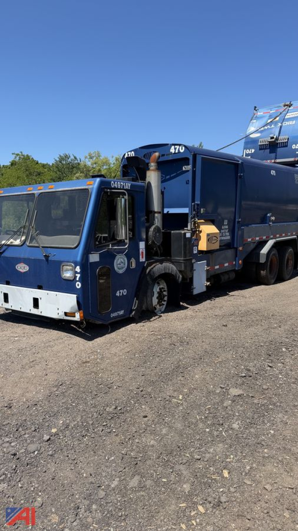 Crane Carrier garbage truck side-view showing blue body with compactor and arm, 470 number on cab, debris container, and side loader mechanism.