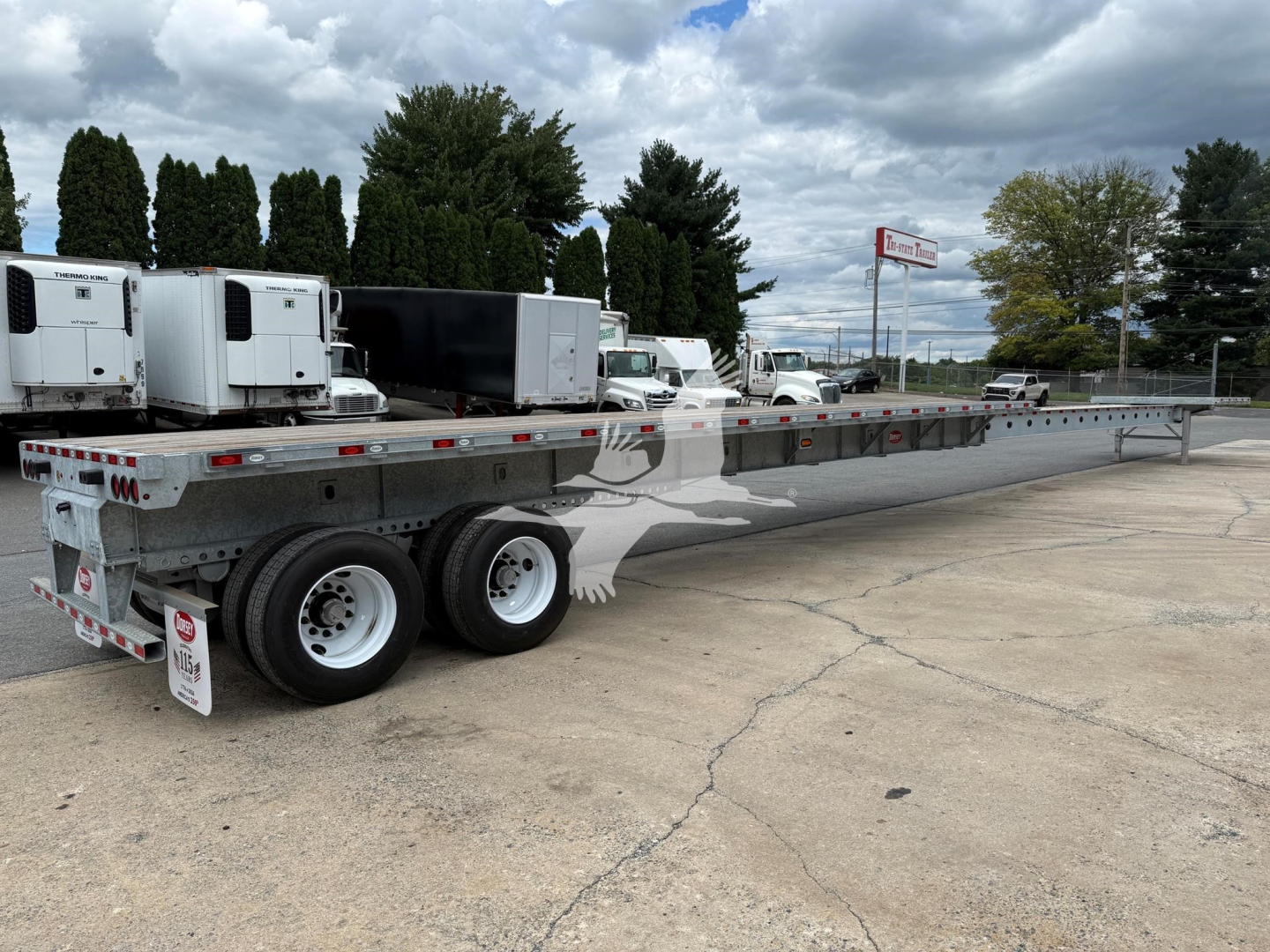 Flatbed trailer with extended long bed showing dual rear axles and gooseneck area.