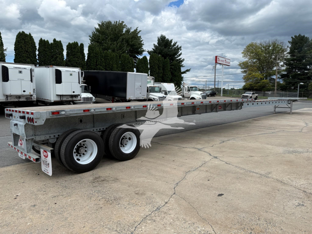 Flatbed trailer with extended long bed showing dual rear axles and gooseneck area.