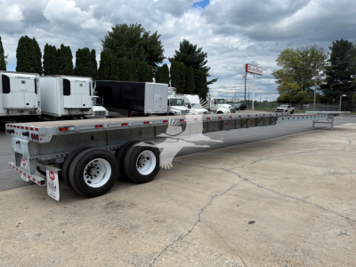 Flatbed trailer with extended long bed showing dual rear axles and gooseneck area.