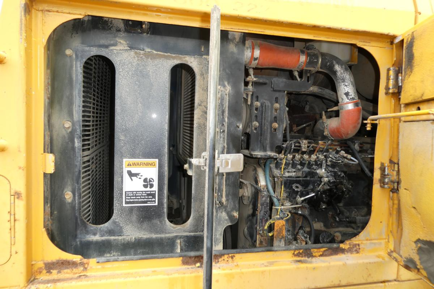 Kawasaki 65TMV wheel loader engine bay view showing air intake grille, hoses, and engine components with yellow machine frame.