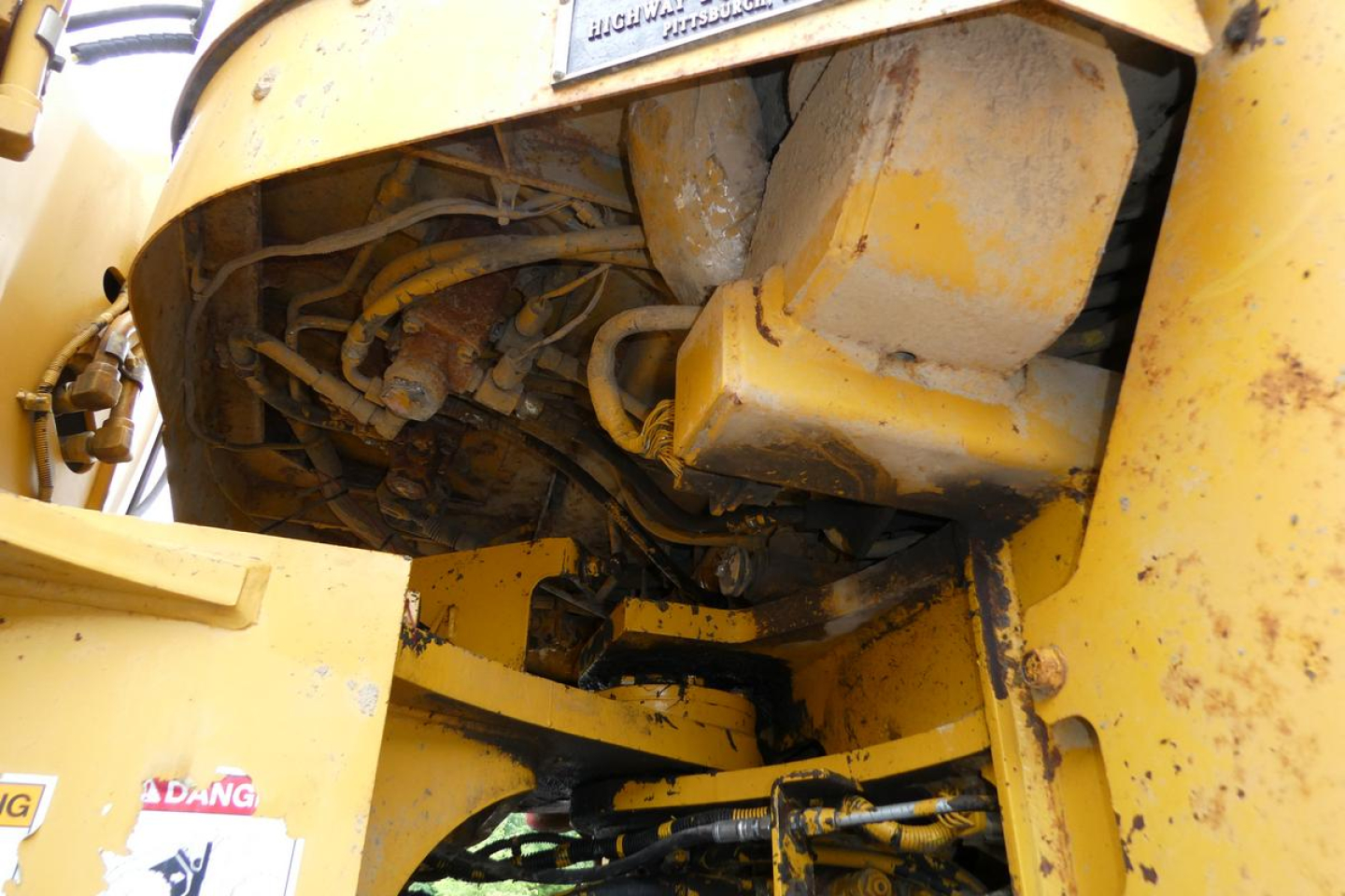 Kawasaki 65TMV wheel loader engine bay showing hydraulic hoses and under-hood components.