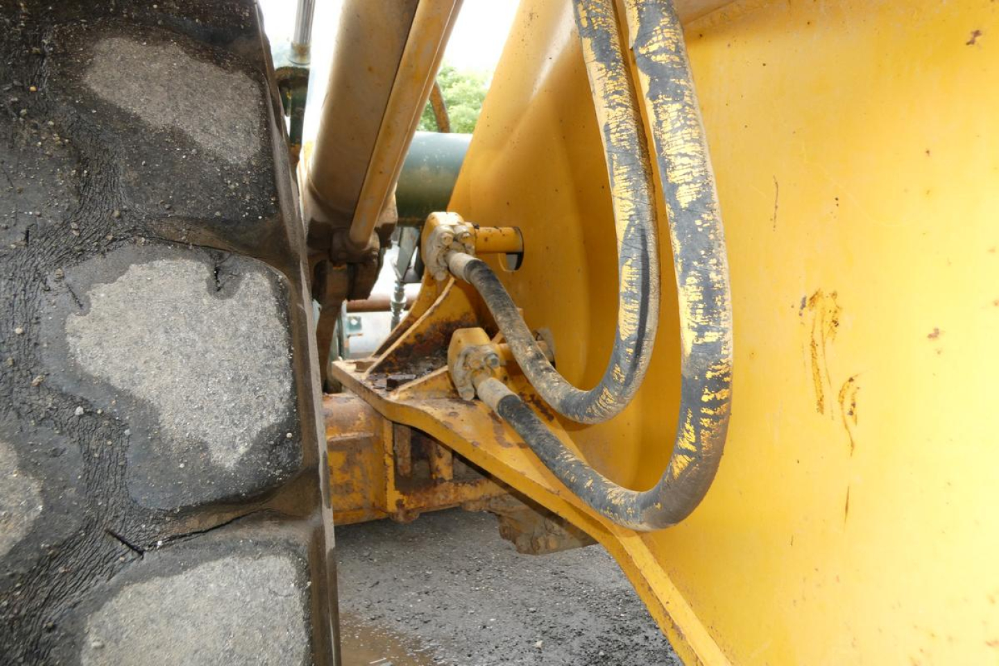Kawasaki 65TMV wheel loader side view showing hydraulic hoses and yellow boom linkage near large tire.