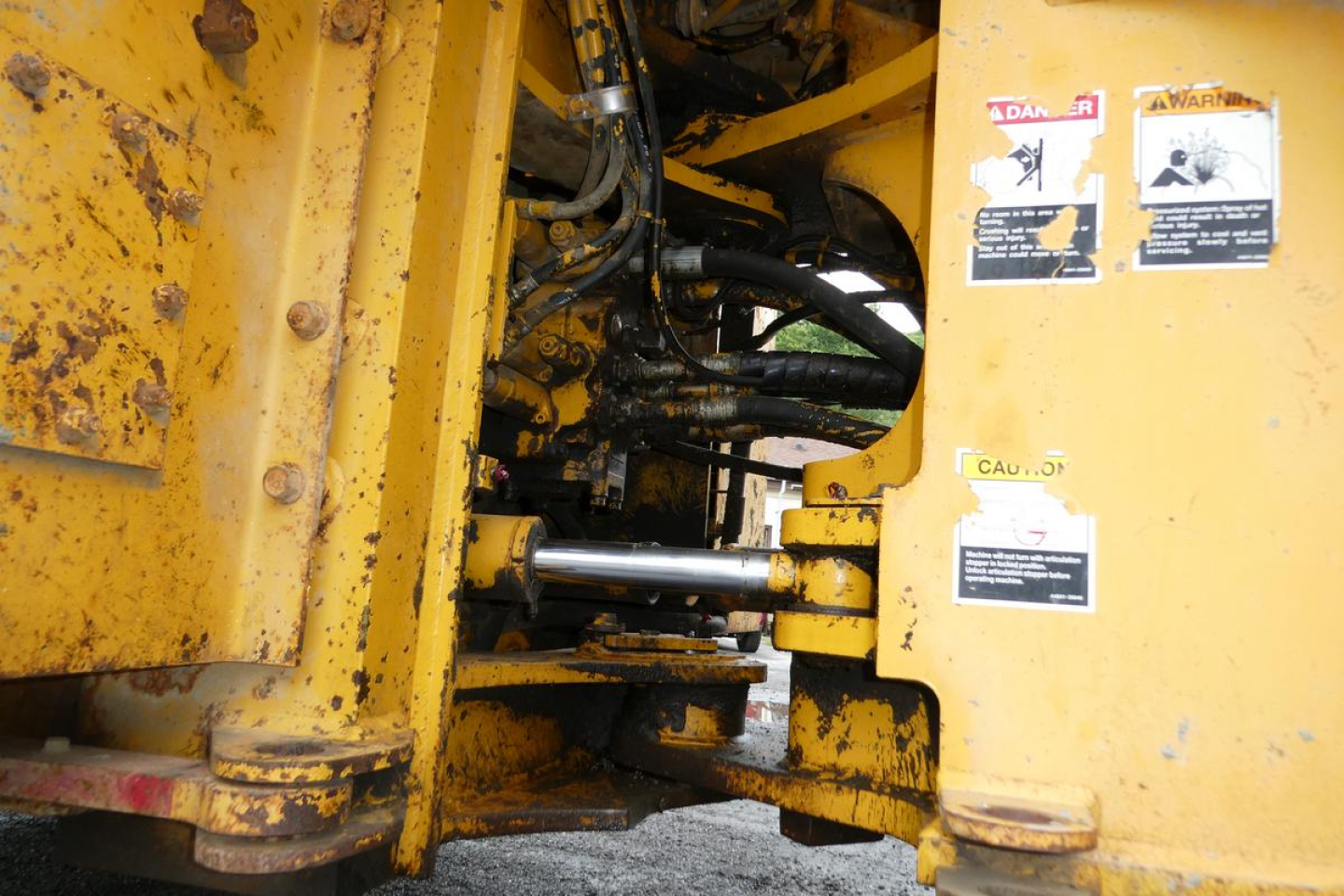 Wheel loader interior framework with hydraulic hoses and warning labels on yellow painted metal components.