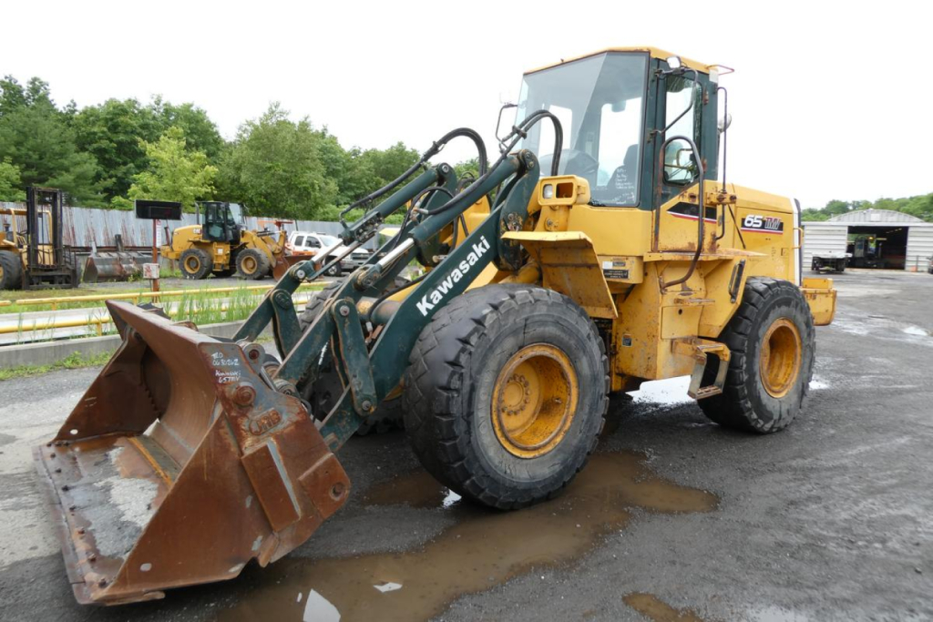 Kawasaki 65TMV wheel loader in service with front bucket and hydraulic arms visible.
