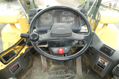 Kawasaki steering wheel and dashboard inside a 2007 Kawasaki 65TMV wheel loader cabin showing gauges and controls.