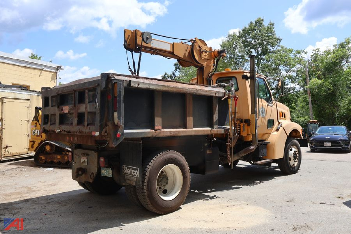 Dump truck rear/side view with loaded dump bed and crane on top; visible brand label on tire reads 'Steico' and there are no other legible texts.