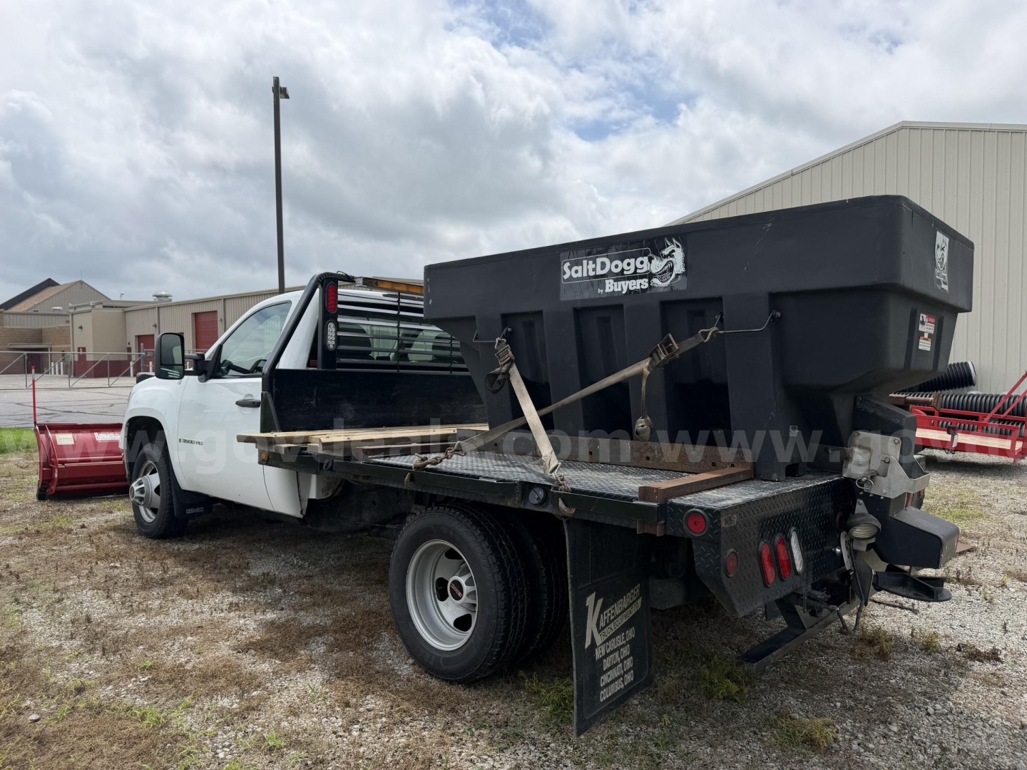 White GMC Sierra 3500HD utility truck with a black SaltDogg spreader attached in bed, side view showing rear and taillights.