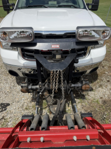 Trucks showing front view of a white 2009 GMC Sierra 3500HD with plow mounting hardware and Western plow attachment; front bumper chrome details and tow hooks visible.