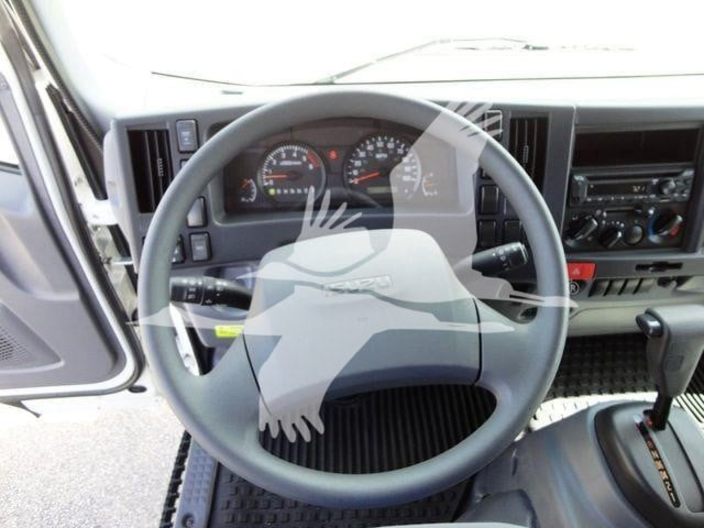 Isuzu NPR HD truck cab interior showing steering wheel and dashboard with gauges and controls.