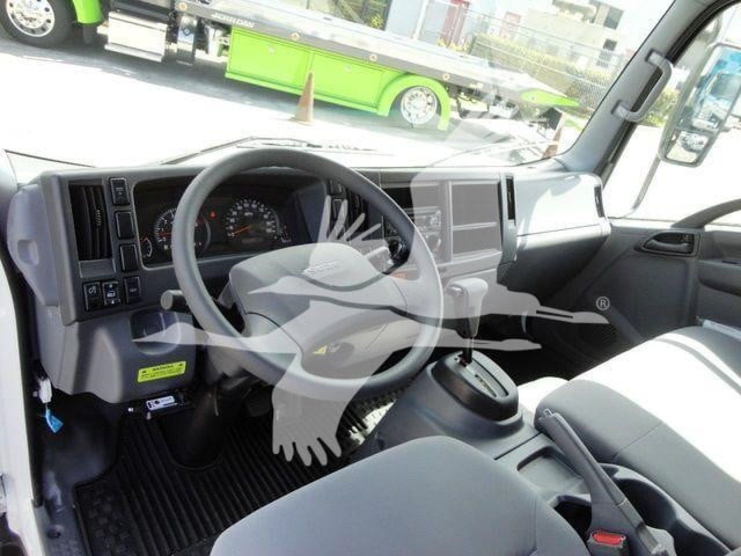 Isuzu NPR HD truck cabin interior showing steering wheel, dashboard, and center console with touchscreen display.