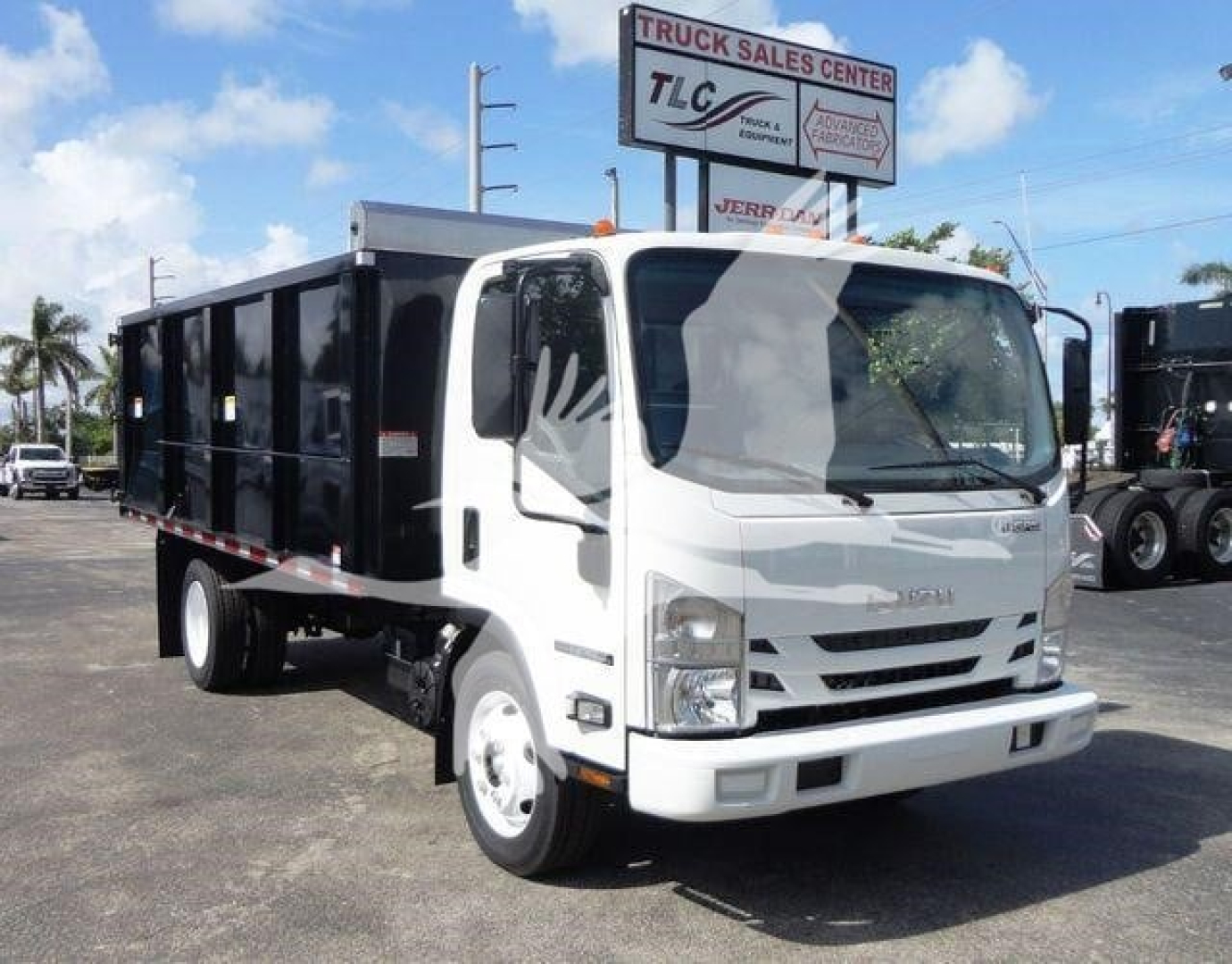 Isuzu NPR HD dump truck in white with black dump bed, front view showing cab and cargo bed