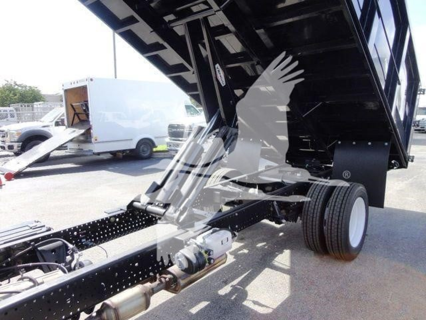 Isuzu NPR HD dump truck chassis showing raised dump bed with hydraulic cylinder and rear dual wheels.