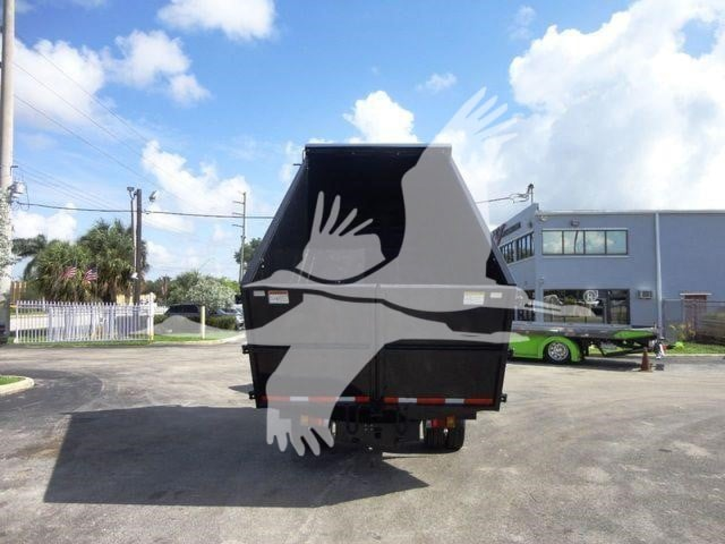 Isuzu NPR HD dump truck rear view showing dump bed and hitch with blue sky