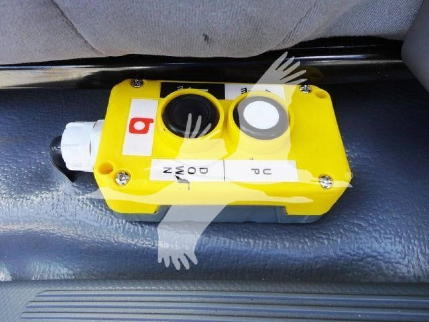 Isuzu NPR-HD truck interior with a yellow safety mechanism or valve block mounted on the floor under the seat; labels and dials visible.