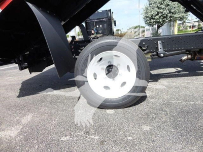 Wheel and suspension of a 2023 Isuzu NPR HD dump truck chassis showing front wheel and leaf spring components.