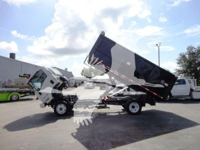 Isuzu NPR-HD dump truck with tilted dump bed in service showing hydraulic mechanism.