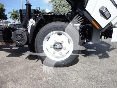 Isuzu NPR HD front-left wheel well and engine bay with white wheel, black chassis, and cab tilt visible.