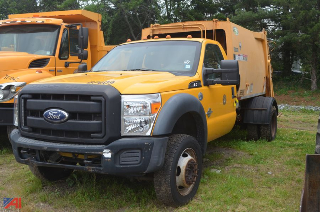 Ford F-550 Super Duty Packer Truck in field showing front grille and side view.