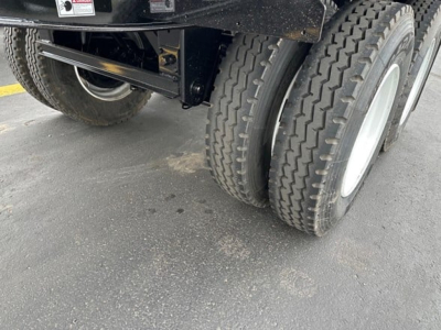 Dual rear wheels of a jet side-dump trailer showing tire treads and part of the undercarriage with a black frame.