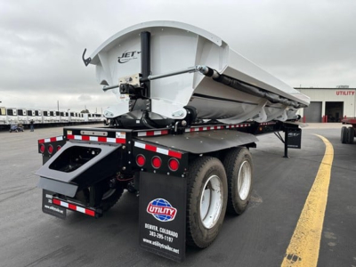 Jet side dump trailer showing rear view with white tank, dual rear axles, and Utility logo. Visible text: JET on the hopper, Utility branding on mudguard, wheels, and rear bumper.