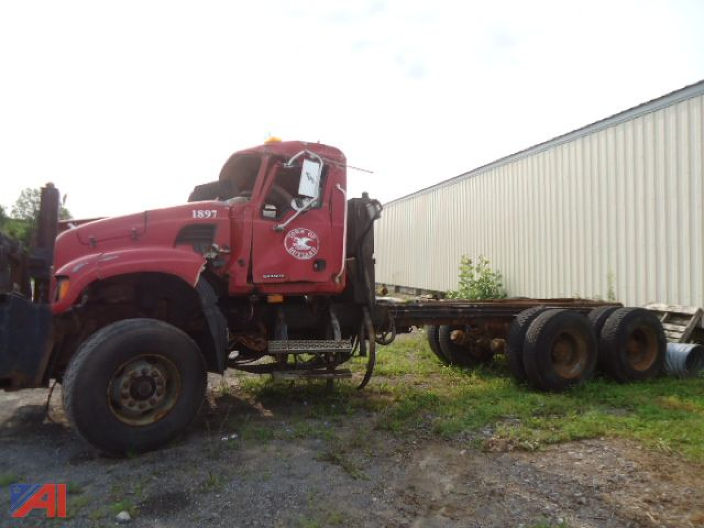 Dump truck cab and chassis with Wing, red Mack Granite CV713, side view, with long wheelbase trailer frame on an outdoor lot.