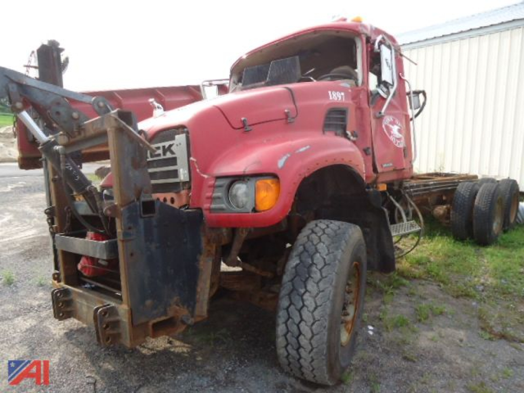 2005 Mack Granite CV713 dump truck cab and chassis with wing seen from front-left,
