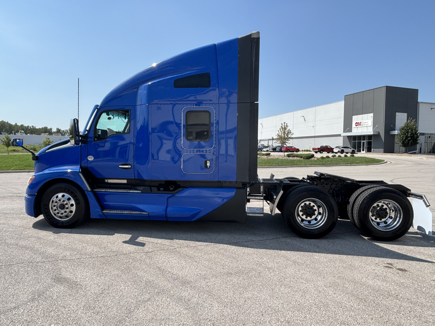 Kenworth T680 sleeper cab tractor in blue, side view, with dual rear axles and black accents.