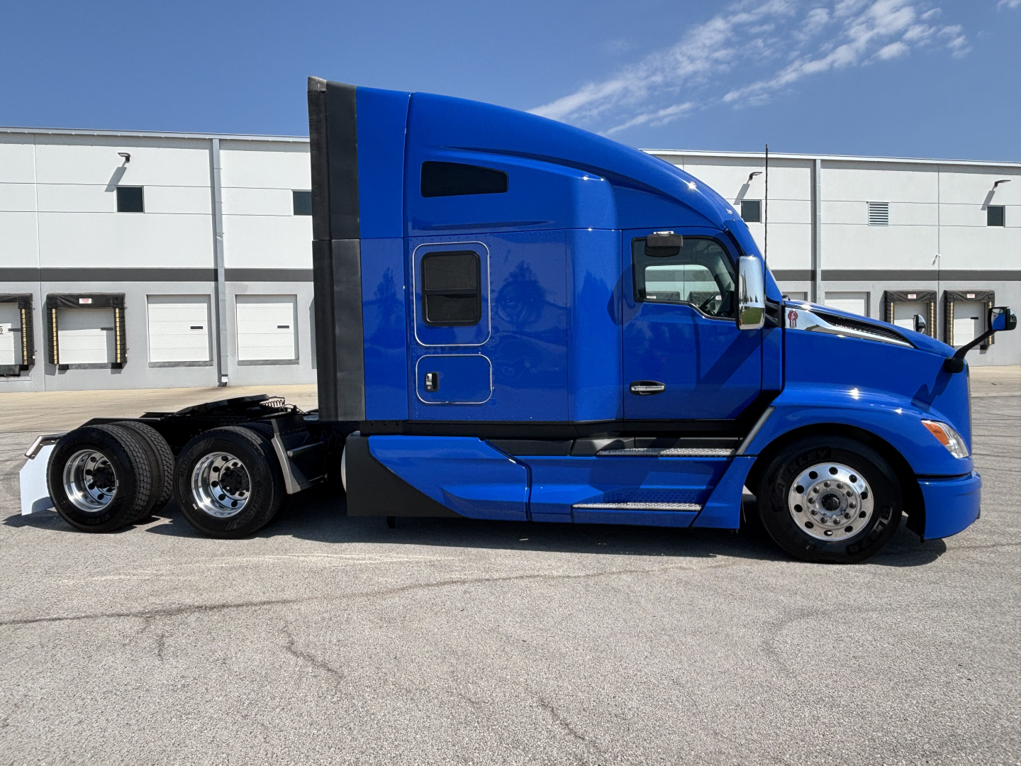 Kenworth T680 truck side view showing blue sleeper cab and chrome wheels.