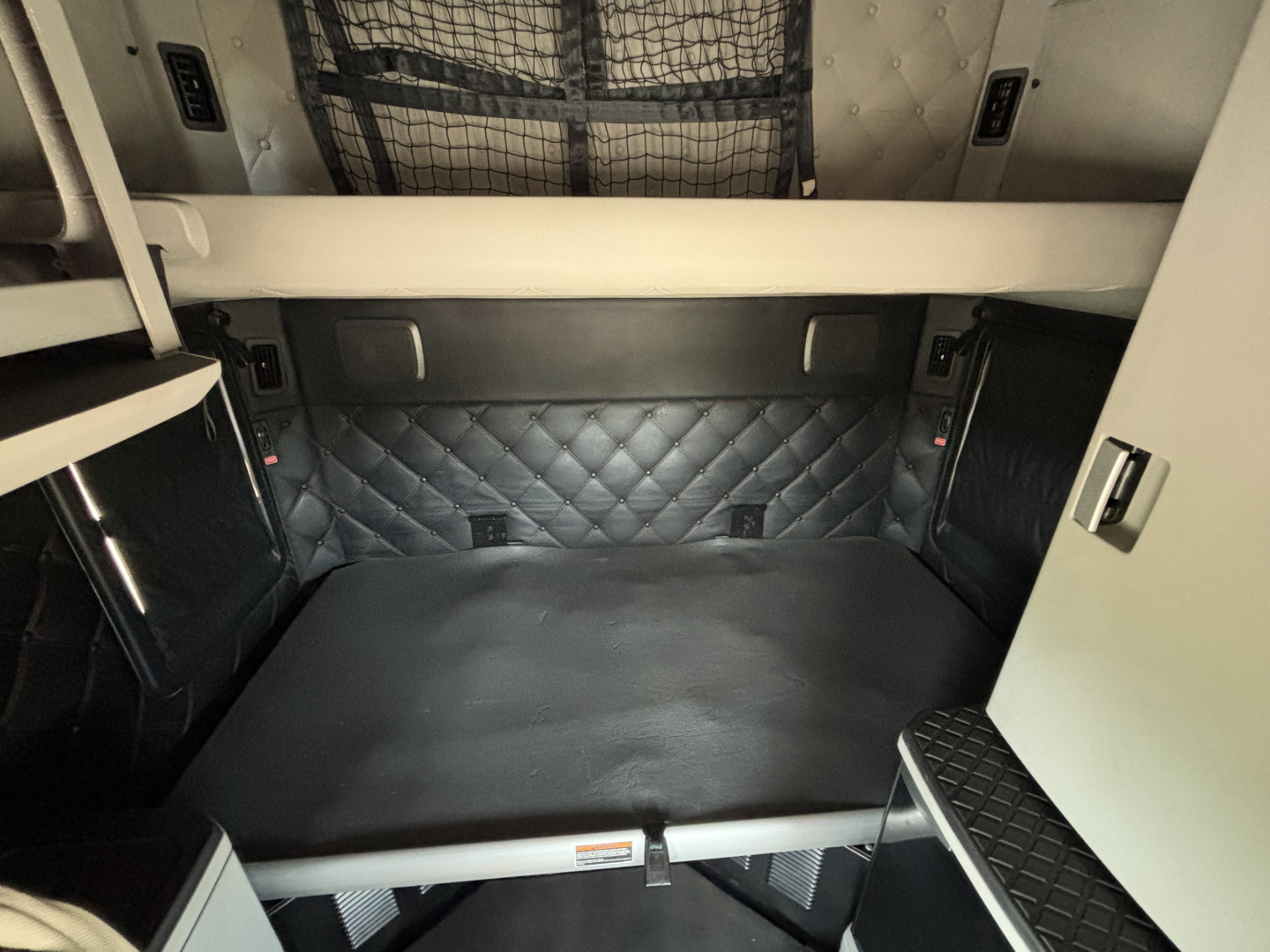 Kenworth T680 sleeper cab interior cargo area with quilted padding and storage compartments.