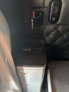 Kenworth T680 cab interior showing a small center console with a dual-drawer unit and quilted black upholstery.