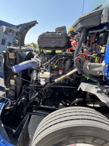 Kenworth T680 engine bay showing air intake hoses and engine components.