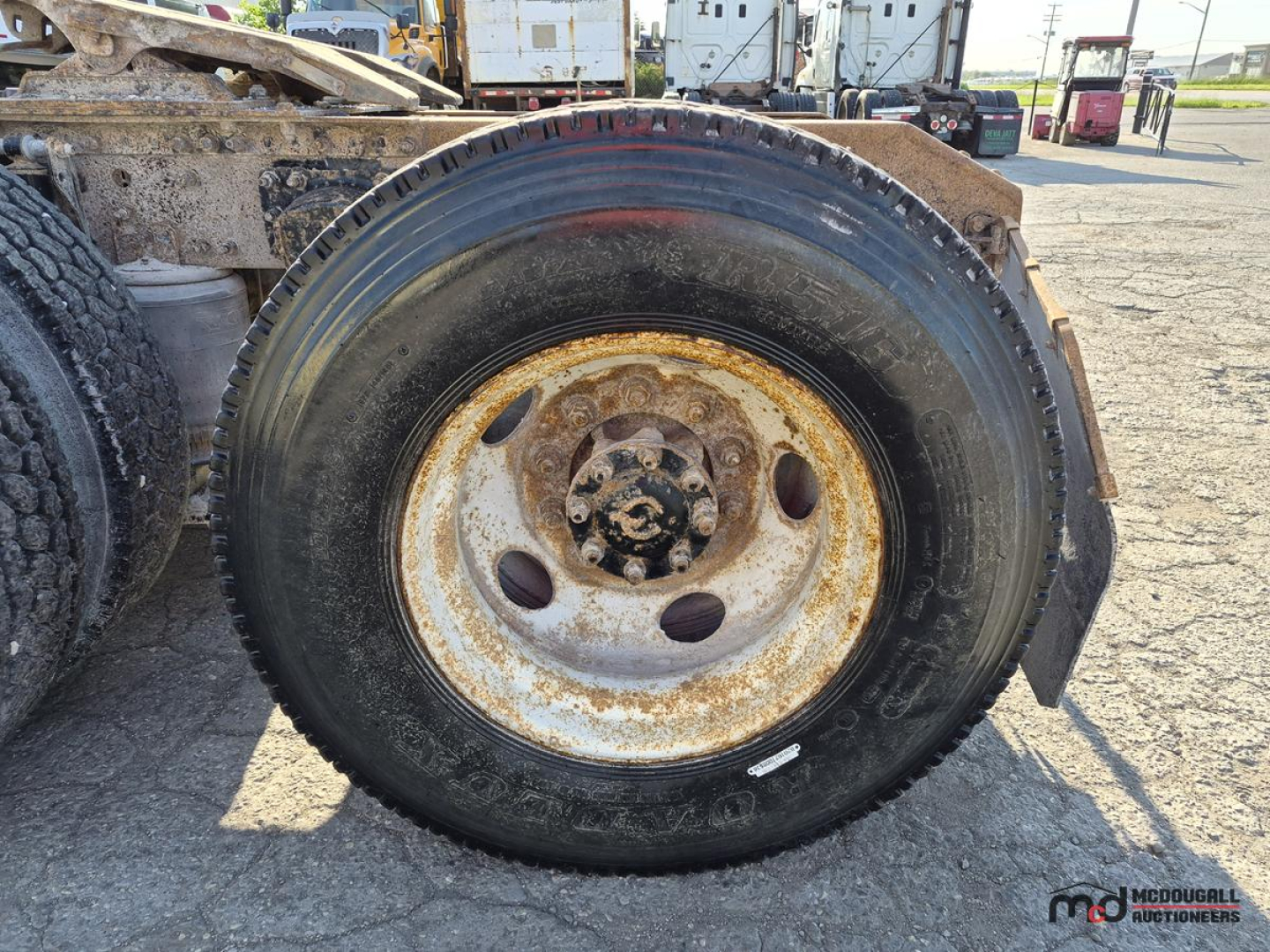 Wheel and tire of a Volvo semi truck with rusted rim and black tire. No legible text visible on components.