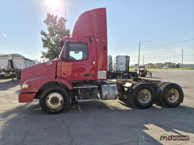 Volvo 2005 day cab semi truck side view showing cab, fuel tanks, rear tandem axles, and exhaust stack.