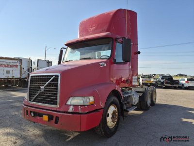 Volvo day cab semi truck in red with large sleeper, front grille, and Volvo emblem; side view shows dual rear axles and front hood; windshield with side mirrors.