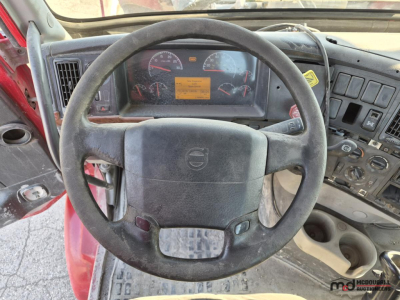 Volvo truck interior steering wheel and dashboard view showing gauges and center panel.
