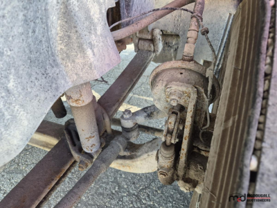 Volvo truck front suspension and brake assembly with road grime and metal components visible.