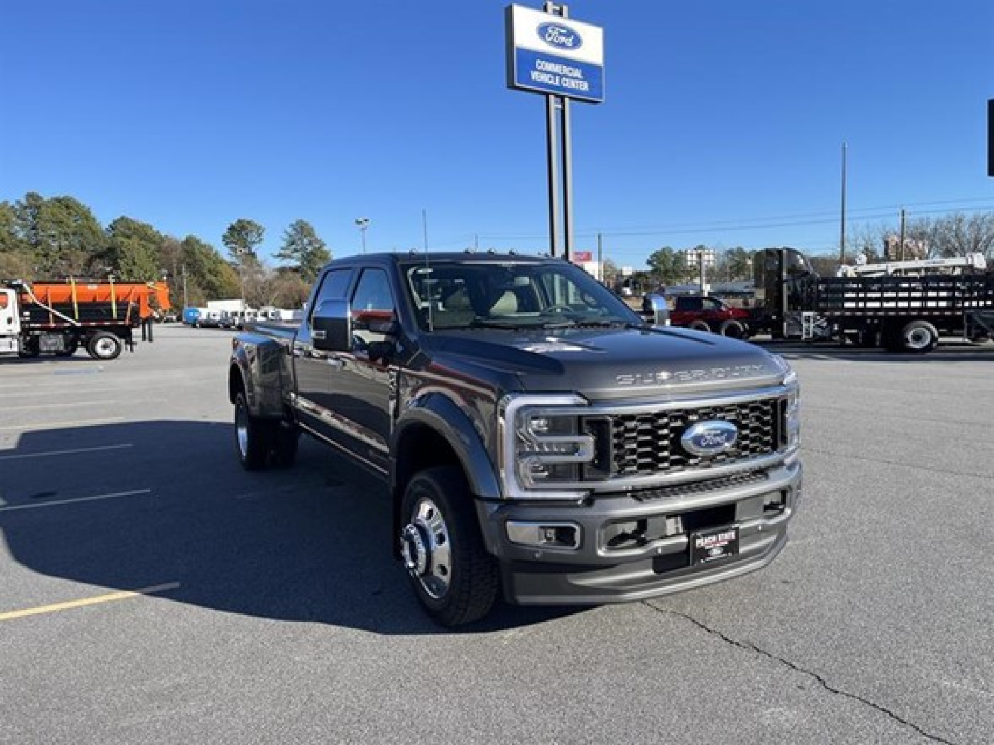 Ford F-450 pickup truck in dealership lot, front three-quarter view, with Ford emblem grille and dealership sign in background.