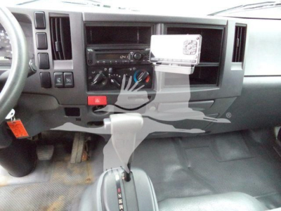Isuzu NPR truck cabin interior showing dashboard controls, gear shift, and a mounted device with a white screen.