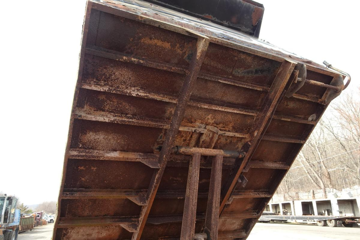 Dump truck bed tilt with rusted metal surface and hydraulic support in view.