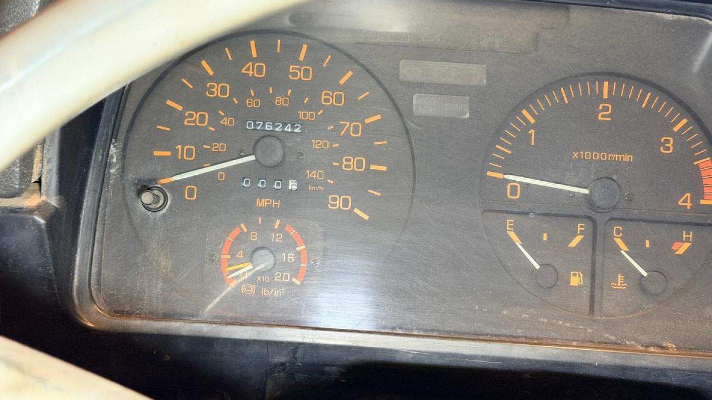 Dashboard of a 1993 Mitsubishi FH dump truck showing speedometer, tachometer, fuel gauge, and warning indicators. Text includes MPH scale, x1000/min, and various gauge markings.