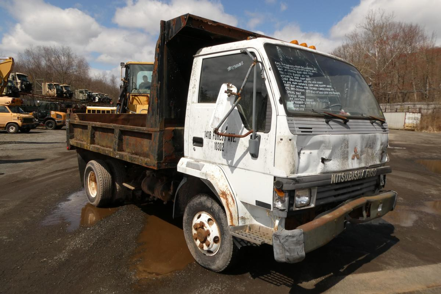 Mitsubishi FH dump truck in service showing front cab and cargo bed with writing on windshield and side panel.