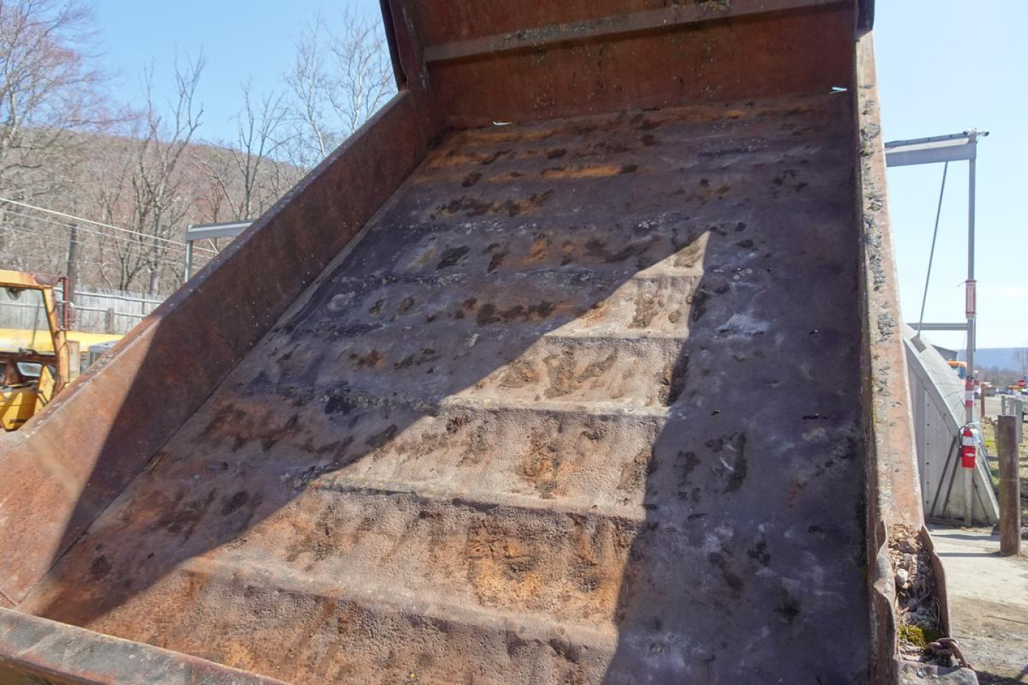 Dump truck bed interior showing rusted metal surface and ribbed sides.
