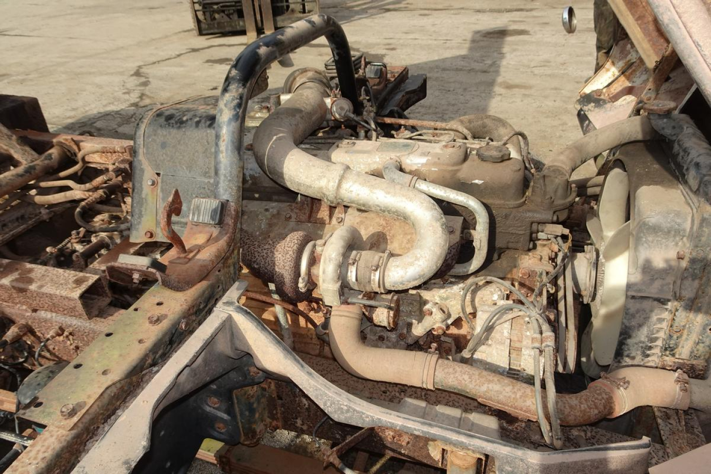 Mitsubishi FH engine bay showing diesel engine with intake piping and turbocharger, exposed hoses and metal frame.
