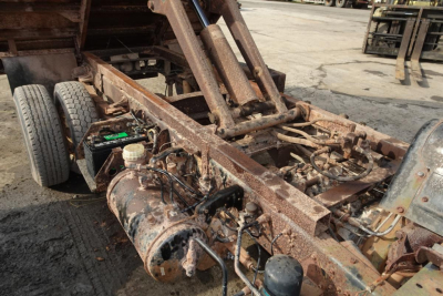 Chassis and hydraulic arm assembly of a Mitsubishi FH dump truck frame showing exposed metal components and a rusty, weathered frame.